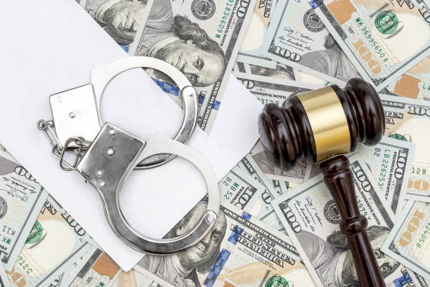 istock Gavel, handcuffs, envelope on background of dollar bills. 1077265832