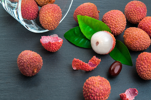 Fresh pile of lychees with leaves on stone background
