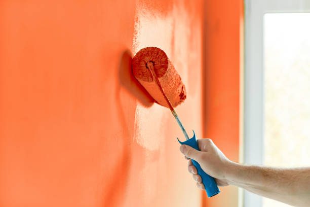 hommes de main peinture mur avec rouleau à peinture. appartement de peinture, rénovation avec de la peinture de couleur orange rouge - painting wall paint paint roller photos et images de collection