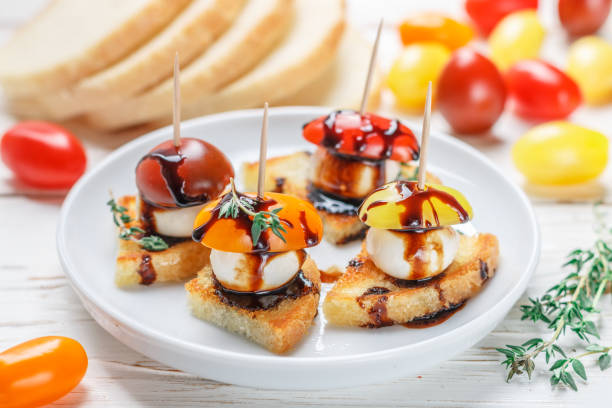 le pain de pain grillé avec tomate cerise, mozzarella, thym et balsamique sur fond en bois blanc. canape. bruschetta. snack gastronomique. mise au point sélective - baguette vinegar balsamic vinegar glazed photos et images de collection