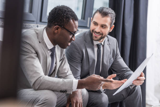 istock multiethnic businessmen sitting on couch and discussing business document 1077293730