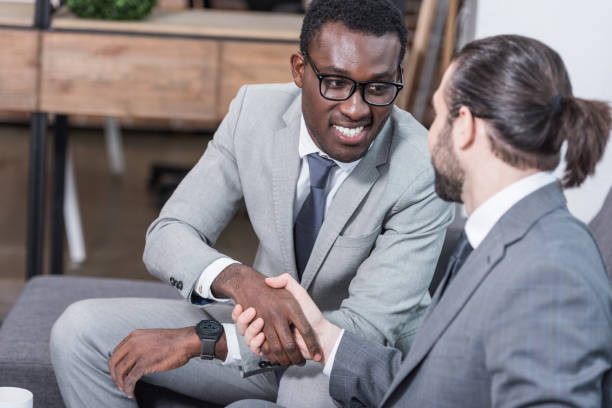 istock multiethnic business partners sitting on sofa and shaking hands 1077293748