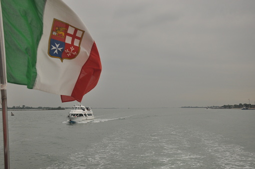 Flag of Italy with coat of arms.Prom flowing through the bay to Venice.