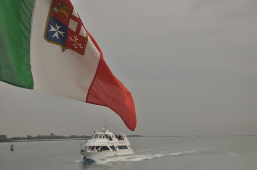 Flag of Italy with coat of arms.Prom flowing through the bay to Venice.