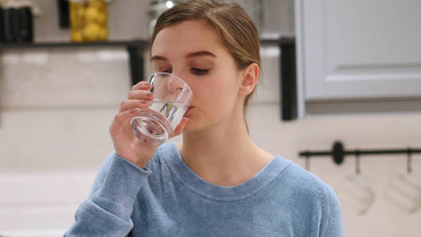istock Woman Drinking Water from Glass at Home 1077313440