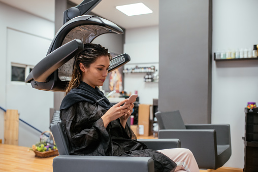 Woman in a professional hairdresser infrared hair dryer