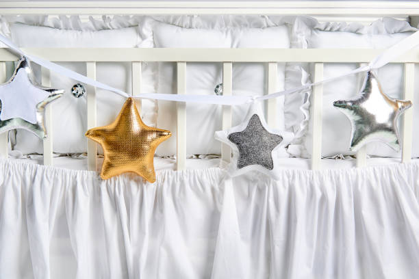 istock Silver, gold and white star shaped pillows on a white baby cot 1077329416