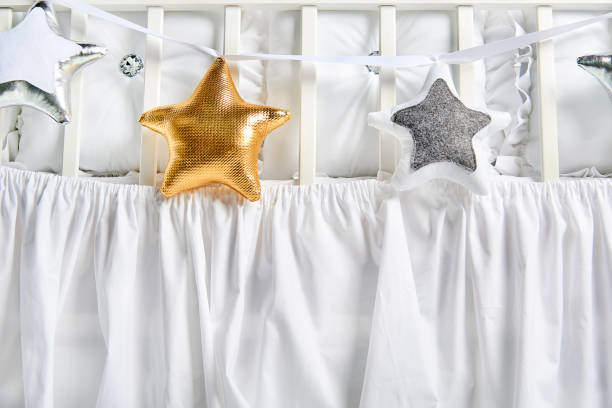 istock Silver, gold and white star shaped pillows on a white baby cot 1077329426