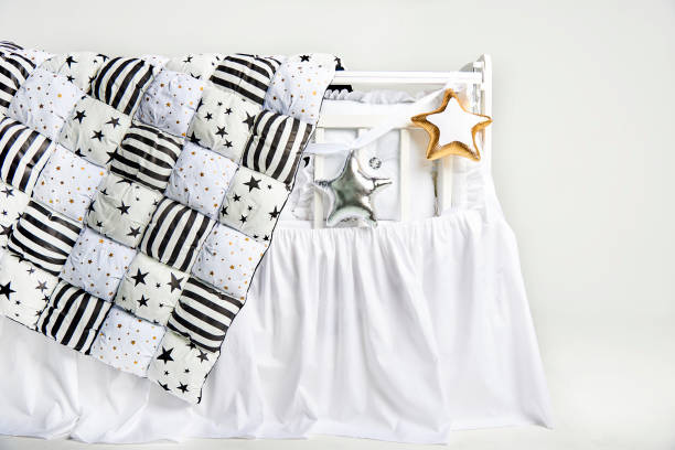 istock Silver and gold star shaped pillows and patchwork comforter on a white baby cot 1077329520