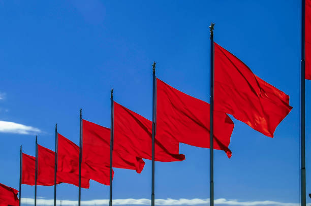 istock Row of red flags on poles blowing in the wind under blue sky 1077355446