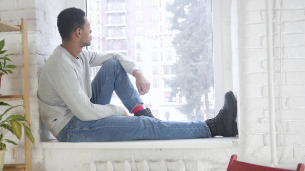 istock Afro-American Man Sitting at Window and and Looking Outside 1077358170