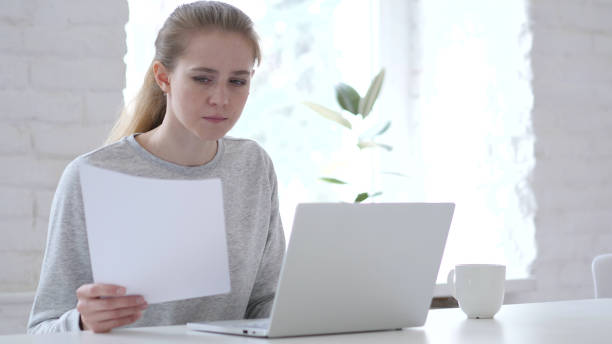 istock Young Woman Reading Document and Gets Upset for Loss 1077361134