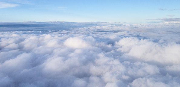 Cloudscape above cloud level view. Blue clear sky over gray clouds