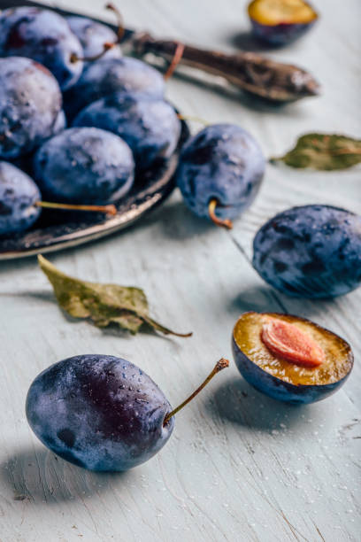 istock Plums with leaves and knife over wooden surface 1077388628