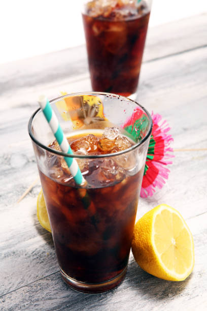 istock Softdrink with ice cubes, lemon and straw in glass 1077394056
