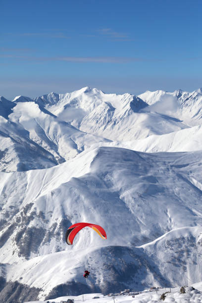 istock Paragliding at snowy mountains over ski resort 1077401412