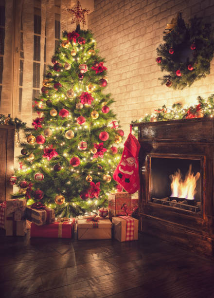 Decorated Christmas Tree Near Fireplace at Home Decorated Christmas tree near fireplace in a cozy festive atmosphere red poinsettia vibrant color flower stock pictures, royalty-free photos & images