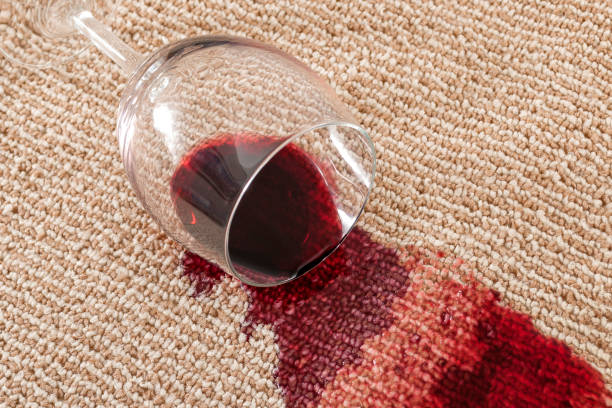 茶色のカーペッ��トに赤ワインのこぼれたガラスを災難と閉じると国内事故概念をホームします。 - spilling ストックフォトと画像