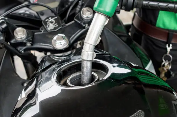 Photo of Close-up of someone refilling gas to the motorcycle barrel tank in gas petrol station.