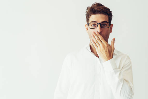 istock Surprised young man covering mouth with hand 1077440326