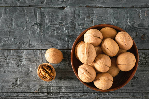 istock Walnuts in a clay bowl on a dark wooden table. Flat lay. 1077458958
