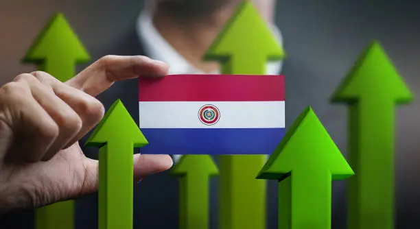 Photo of Nation Growth Concept, Green Up Arrows - Businessman Holding Card Paraguay Flag