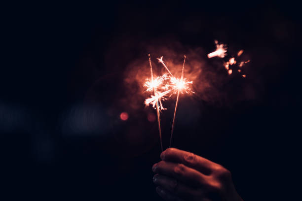istock Hand holding burning Sparkler blast on a black bokeh background at night,holiday celebration event party,dark vintage tone. 1077477938