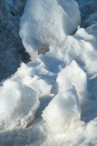 istock Texture, background, pattern. The spring snow melts. The beginning of a warm season, spring. Melting snow on the ground in the city with a mild morning sunlight. 1077486096