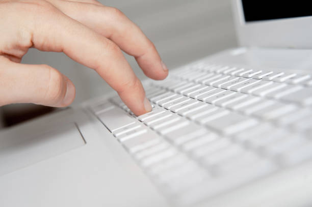istock mans hand typing on white keyboard by fingers. white workspace 1077510546