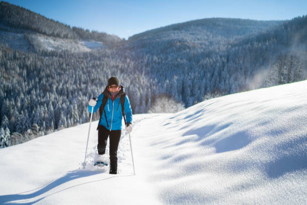 donna in caldi abiti sportivi invernali godendo escursione con le ciaspole nella neve profonda nella soleggiata giornata invernale nel paesaggio rurale - snowshoeing hiking mountain winter foto e immagini stock