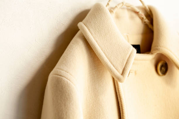 istock white wool coat hanging on clothes hanger on white background 1077520662