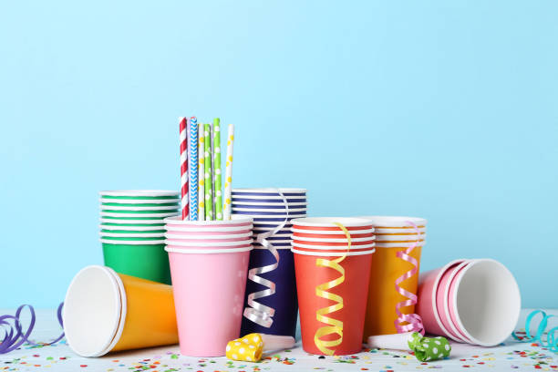 istock Colorful paper cups with straws and confetti on blue background 1077524162