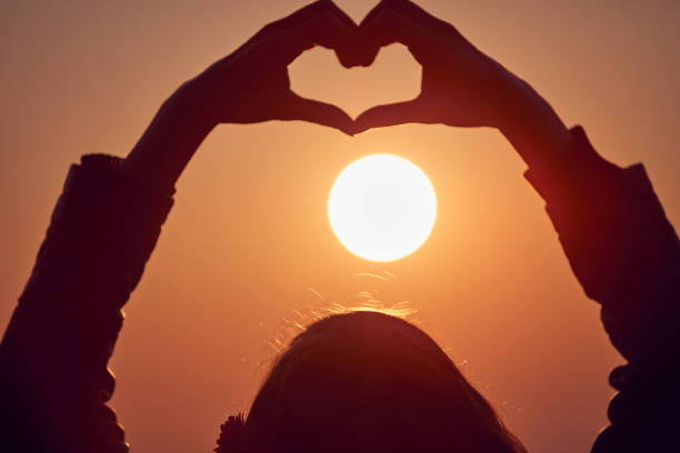 istock Girl making heart - shape sign with hands at sunset / sunrise time. 1077525794