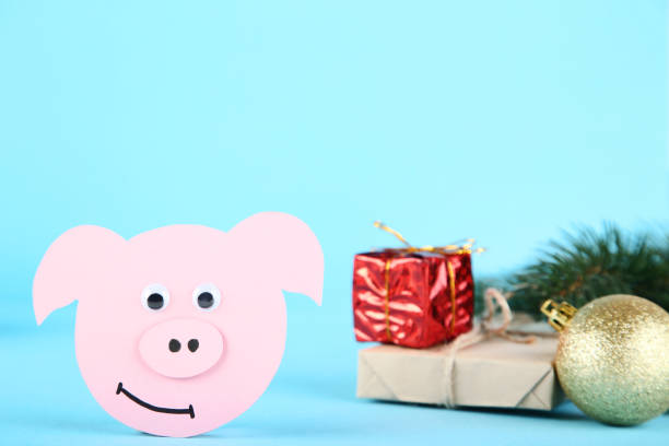 istock Paper pig with gift boxes and bauble on blue background 1077526590