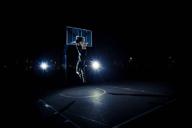 istock Young man playing basketball at night 1077526646