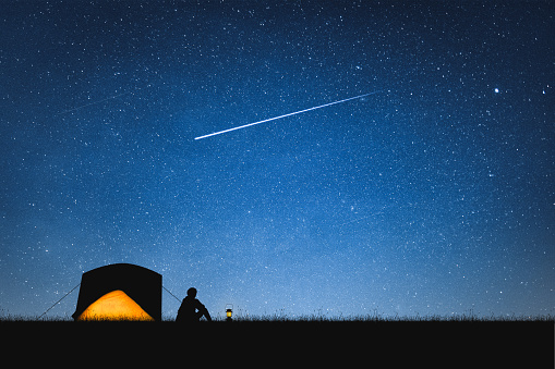 Silhouette of traveler camping on the mountain and night sky with stars. Space background.