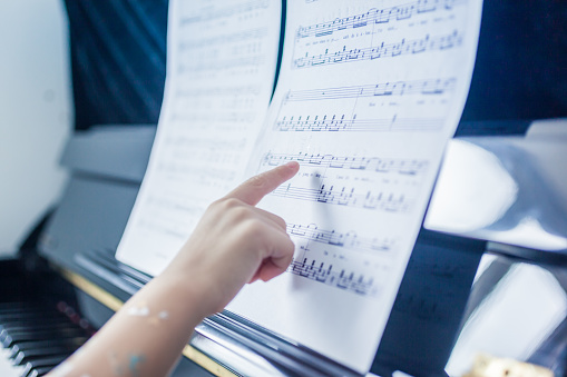 Hand of a Kid Pointing at Sheet Music and Playing Piano