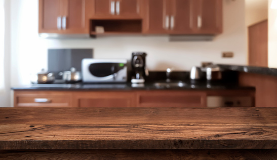Wooden table in front of defocused modern kitchen counter top