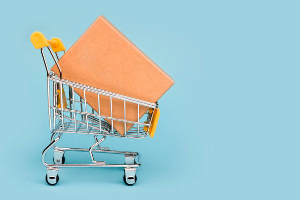 Miniature shopping cart with large box isolated on blue background