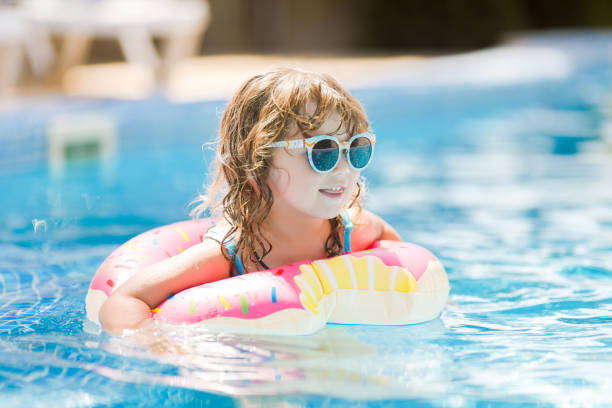 istock Child in swimming pool on funny inflatable donut float ring, learning how to swim. 1077539462