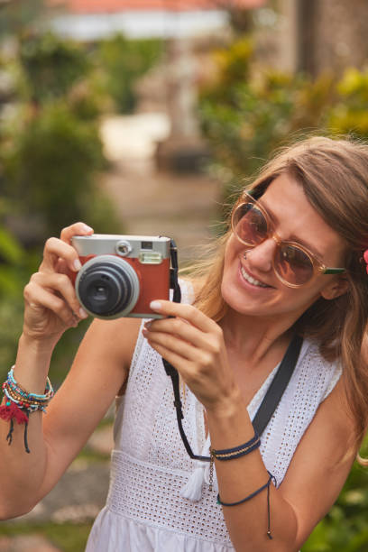 istock Giirl posing with retro vintage camera outdoors. 1077545916