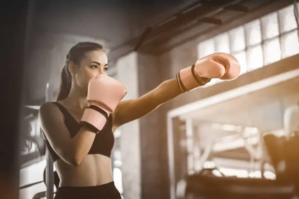 Fit beautiful woman boxer hitting a huge punching bag exercise class in a gym. Boxer woman making direct hit dynamic movement. Healthy, sports, lifestyle, Fitness, workout concept. With copy space.