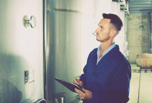 istock Young man in coat taking notes on wine factory 1077557808