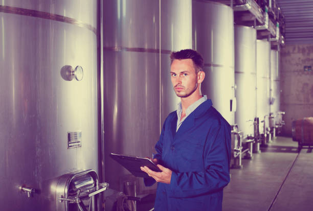 Young man in coat taking notes on wine factory
