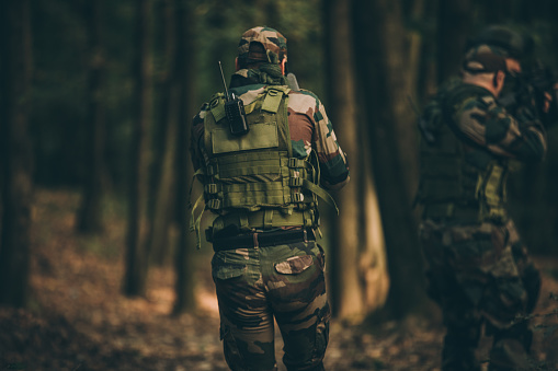 Group of men soldiers in camouflaged clothing deep in wilderness.