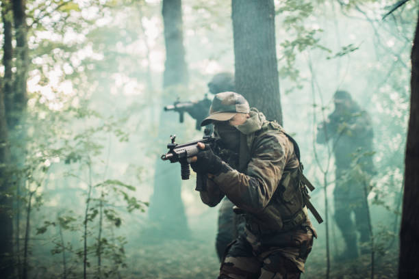 Army team on a mission Soldiers in camouflaged clothing with guns, deep in wilderness on a mission. battlefield photos stock pictures, royalty-free photos & images