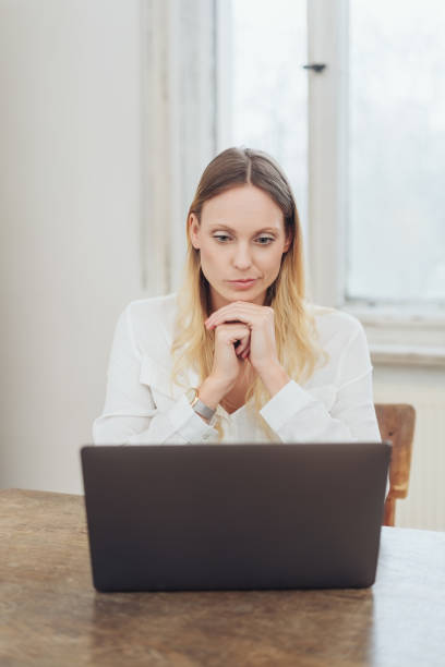 istock Blonde woman sitting with laptop at table 1077571700