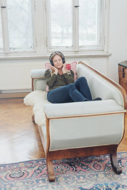 istock Woman listening to music while relaxing on sofa 1077572076