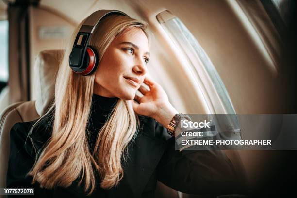 Beautiful Young Woman Listening To Music Through The Headphones In A Private Jet Stock Photo - Download Image Now