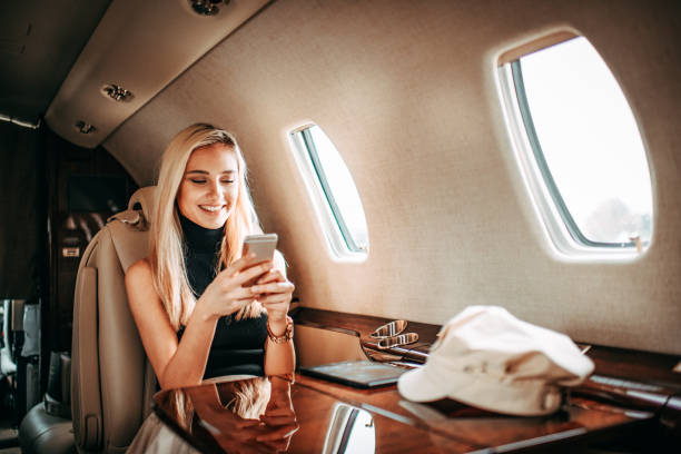 istock Young rich blonde woman using a mobile phone while traveling on a private jet 1077572732